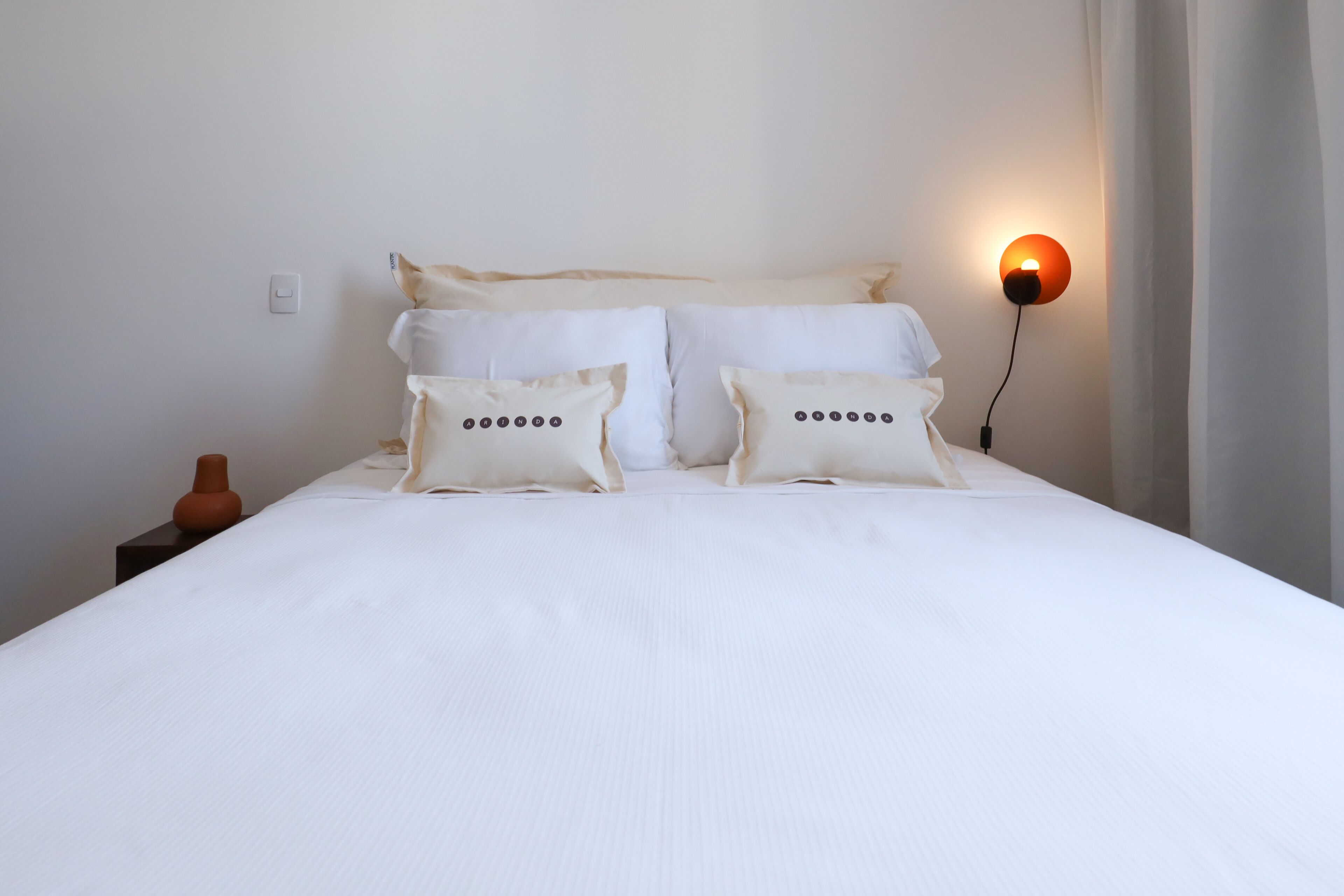 Un lit bien fait, avec une literie blanche et deux coussins décoratifs.