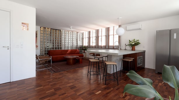 A modern kitchen with a central island, bar stools, and a built-in oven.