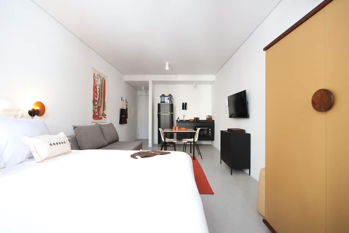 Ein modernes Hotelzimmer mit einem großen Bett, einem Schreibtisch und einer Küchenzeile.