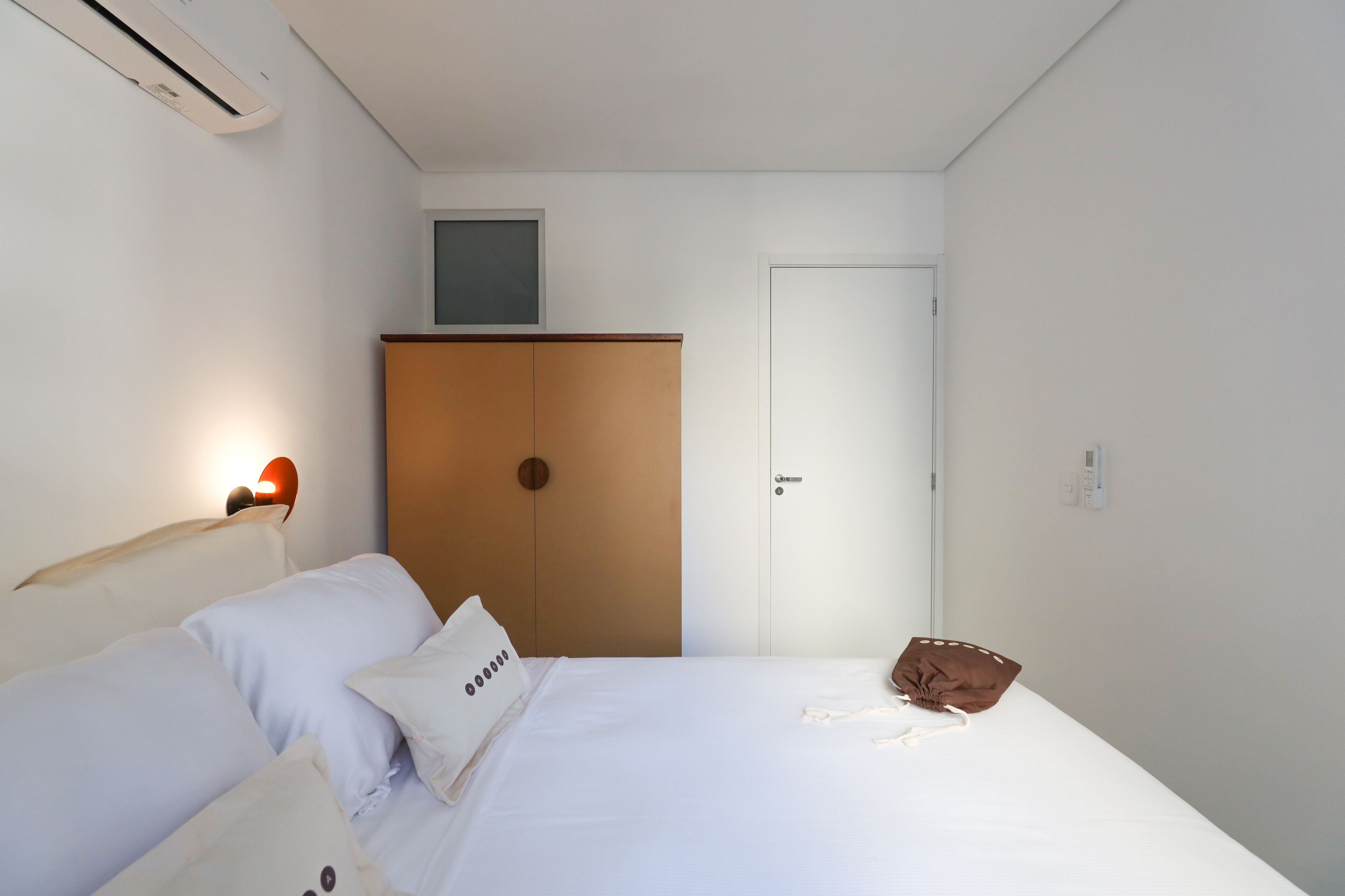 A bedroom with a bed, a wardrobe, a door, and a wall-mounted light.