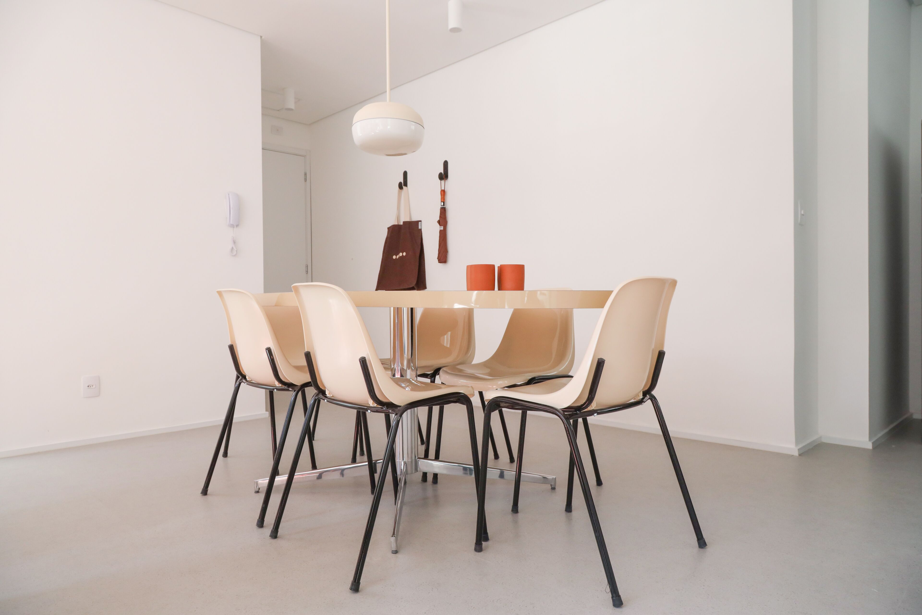 A modern dining area with a white table, six chairs, and a hanging pendant light.
