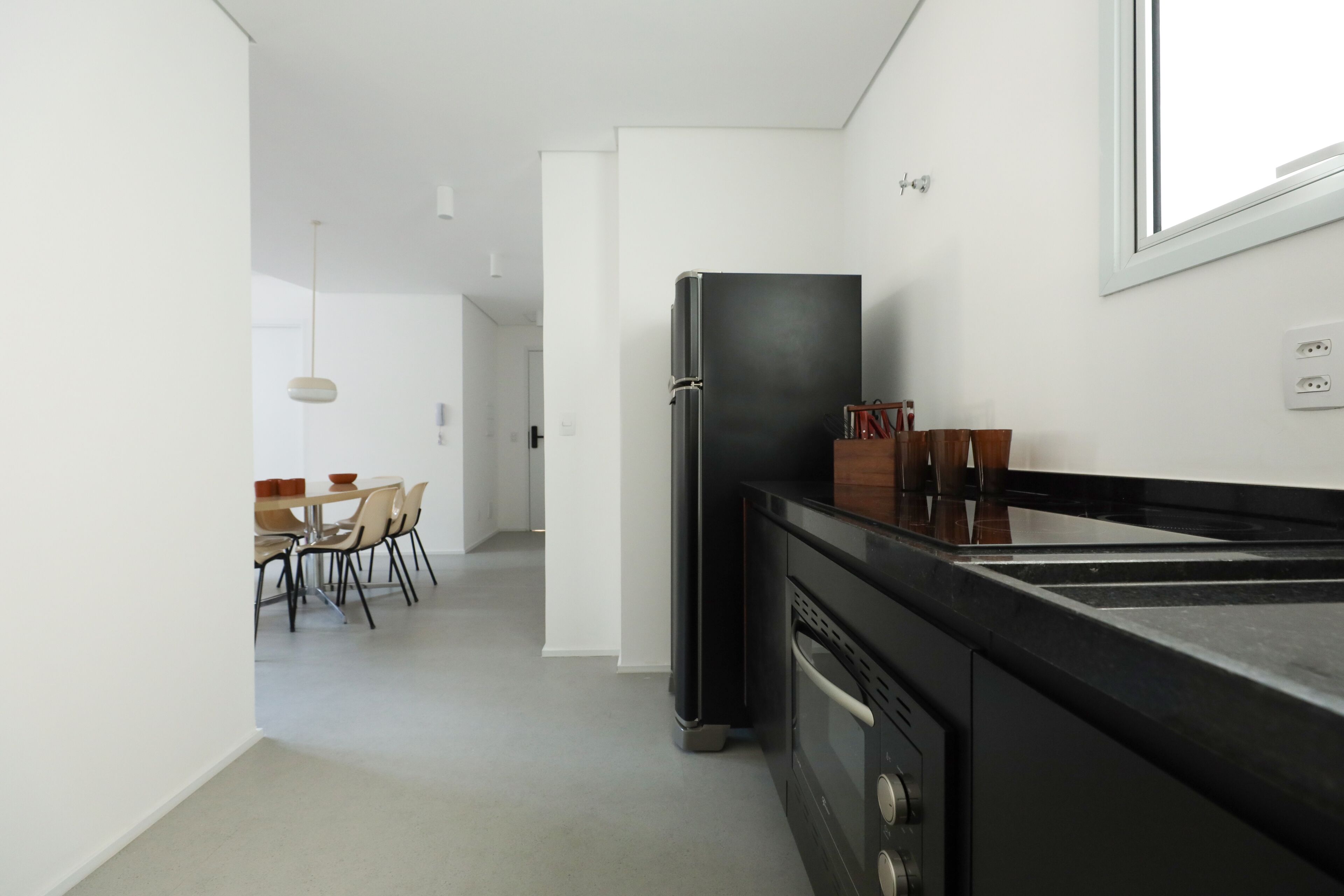Une cuisine moderne avec un réfrigérateur noir, une cuisinière et un coin repas comprenant des chaises et une table.