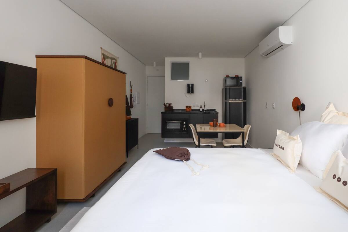 Ein Hotelzimmer mit Bett, Schreibtisch, Kleiderschrank und einer Küchenzeile.