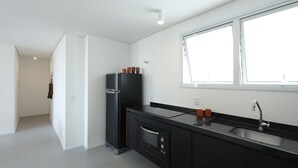 A modern kitchen with a black refrigerator, a built-in oven, and a large window providing natural light.
