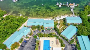 Vista aérea de un resort con varias construcciones, una piscina y un muelle con barcos.