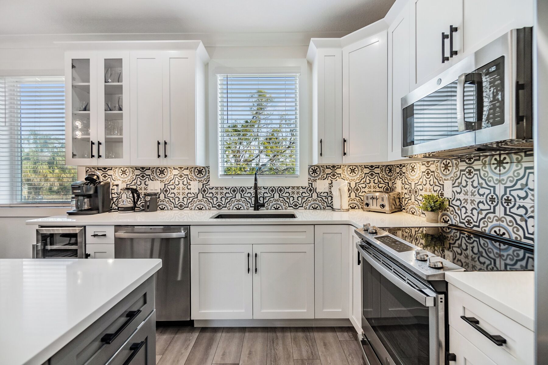 Una cocina moderna con muebles blancos, lavavajillas de acero inoxidable y horno empotrado.