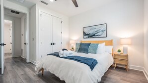Una camera da letto con un letto, comodini, una ventola a soffitto e una porta.