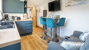 Una cocina moderna con una isla central, taburetes de bar y un televisor de pantalla plana montado en la pared.