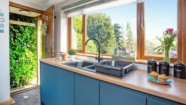 Una cocina moderna con un amplio ventanal, un lavamanos y una encimera con recipientes de almacenamiento.