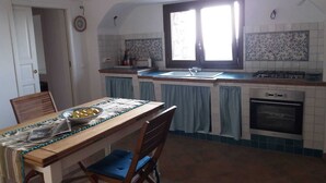 Une cuisine équipée d’une table à manger, de chaises, d’une cuisinière et d’une fenêtre.