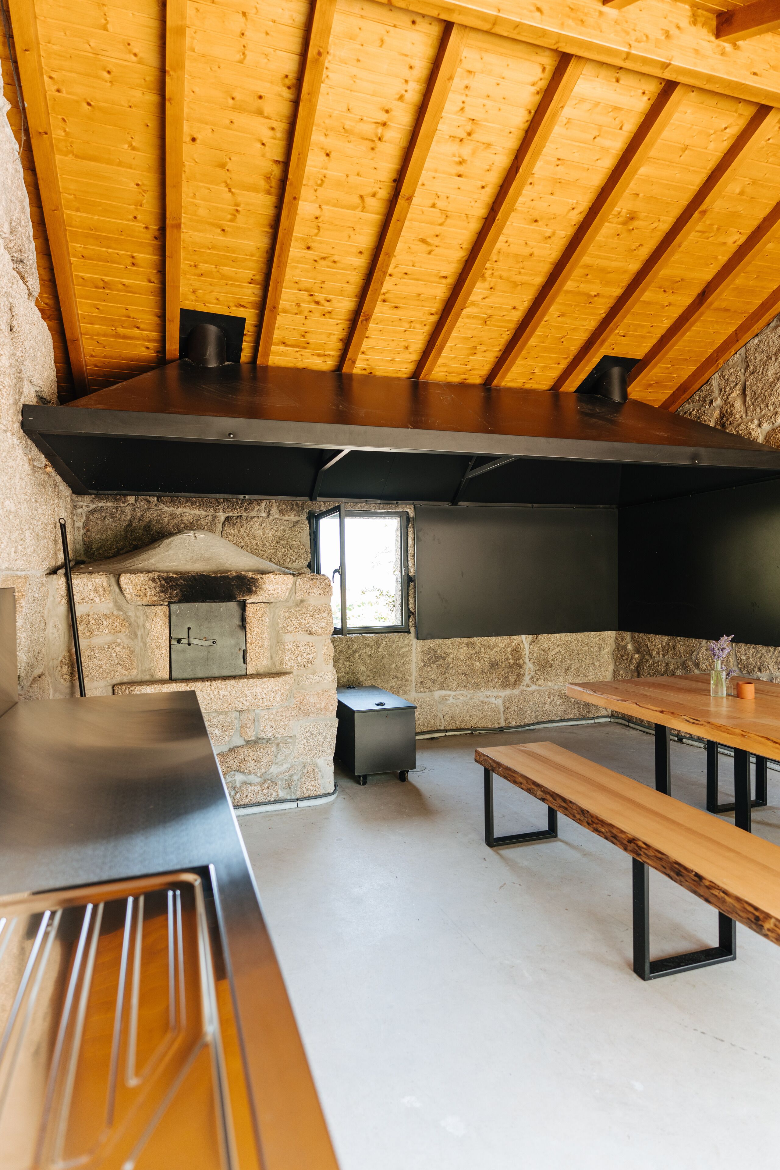 Une cuisine rustique avec un four en pierre, des poutres en bois et une grande fenêtre.