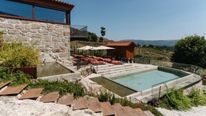 A stone building with a swimming pool, outdoor seating, and a view of the landscape. - D'Autor Village (Baiao)