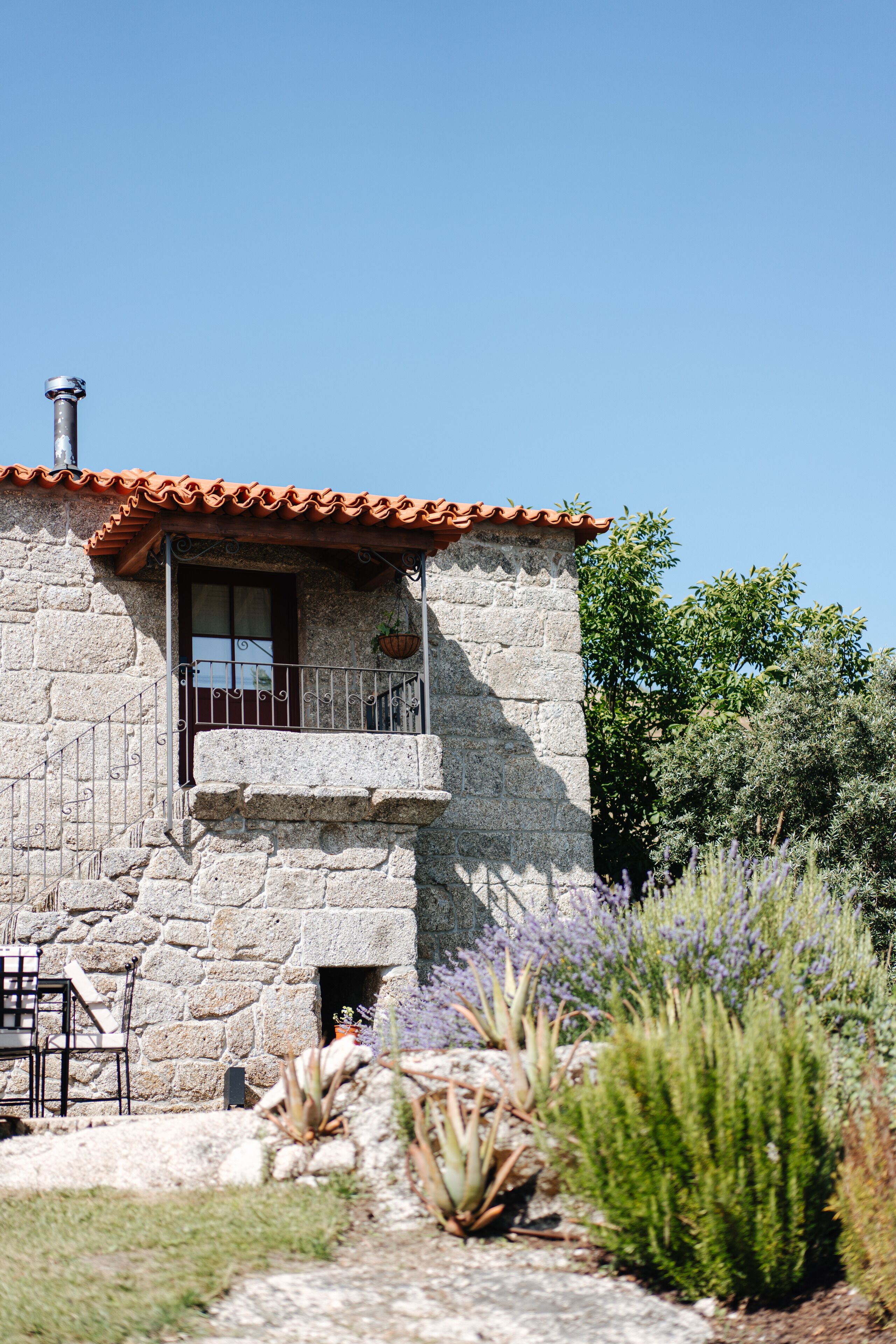 A stone building with a balcony, a window, and a door.