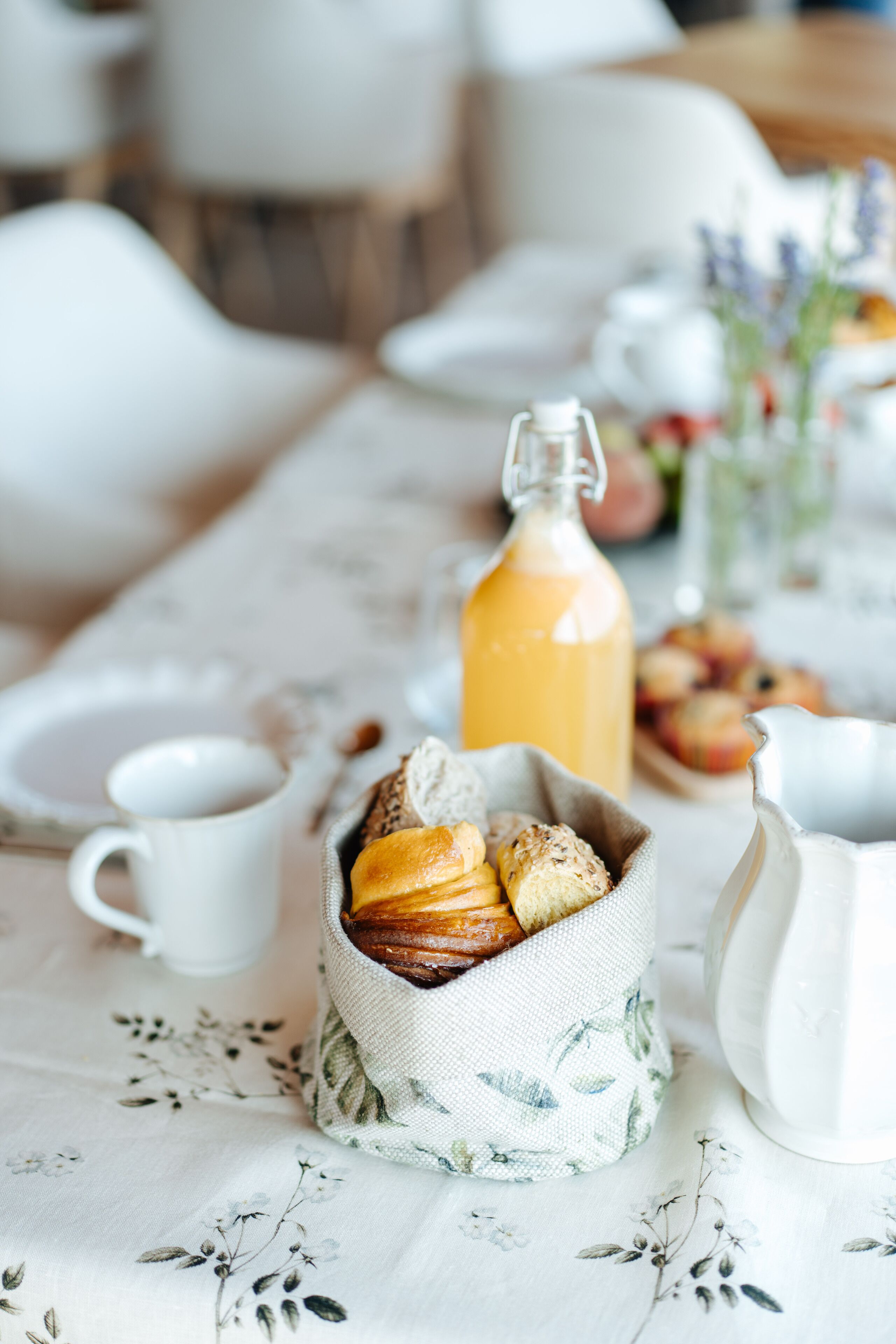 A breakfast setting with pastries, a jug of orange juice, and a white tablecloth.