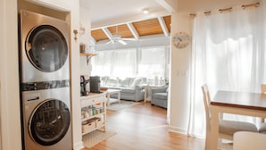 A compact living space with a built-in washer and dryer, a dining area, and a seating area with a sofa and a coffee table.
