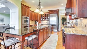 A spacious kitchen with wooden cabinets, stainless steel appliances, and a large island with bar stools. - Riverfront North Augusta Home w/ Private Pool! (North Augusta)