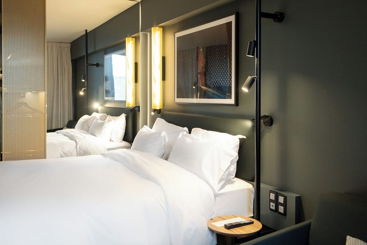 Une chambre d’hôtel moderne avec un grand lit, un petit canapé et un bureau avec une lampe.
