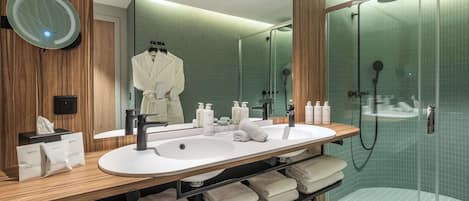 Un baño moderno con tocador de madera, un espejo grande, cabina de ducha de vidrio y toallas dobladas con cuidado.