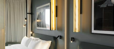 A hotel room with two beds, a large framed picture on the wall, and a modern light fixture.