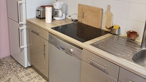 A compact kitchen with a refrigerator, a coffee maker, a toaster, and a wooden cutting board. - Parisian apartment (Paris)