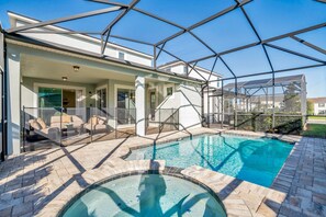 A swimming pool with a glass enclosure, a patio area with outdoor furniture, and a covered seating area.