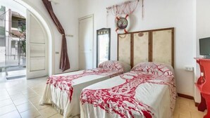 A room with two beds, a large mirror, a clock, and a red cabinet. - Villa Biancarosa - Rosa by BarbarHouse (Porto Cesareo)