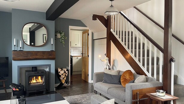 A modern living room with a fireplace, a staircase, and a cozy seating area. - 3 bedroom accommodation in Calbourne (Calbourne)
