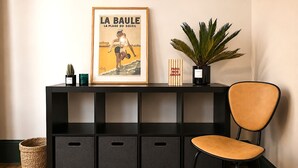 Et sort konsolbord med en indrammet plakat, en potteplante og en stol.
