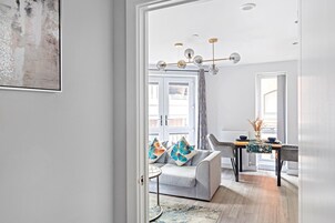 Una sala de estar moderna con un sofá gris, una mesa redonda y un comedor con una mesa y sillas.
