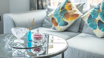 A glass table with a crystal bowl, a blue vase, and a glass container with sticks.