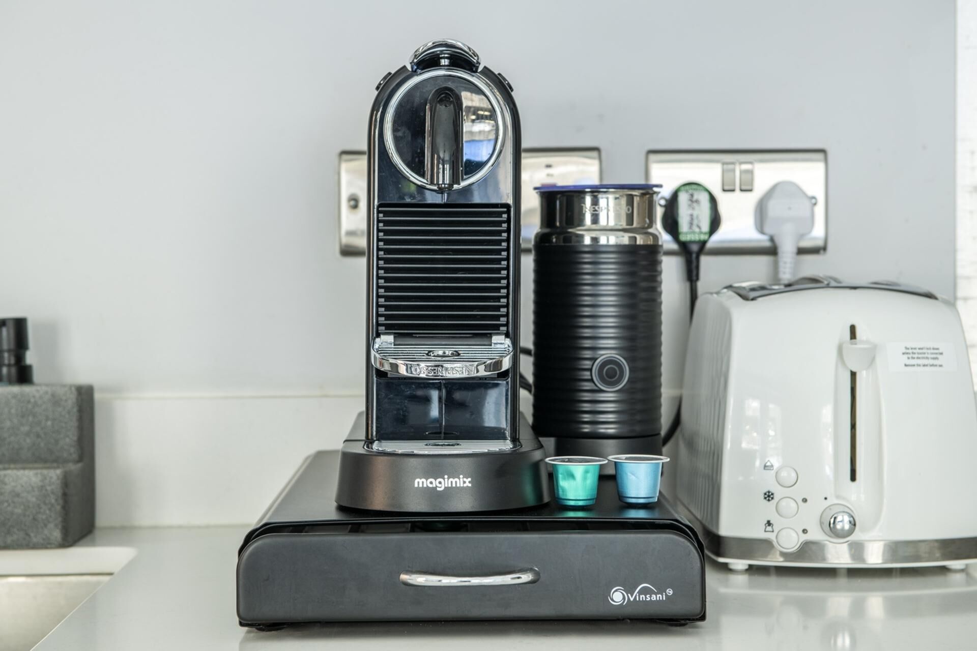A kitchen with a coffee machine, a kettle, and a toaster.