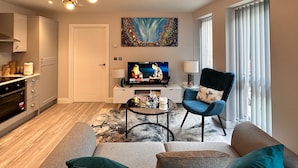 A modern living room with a sofa, armchairs, a coffee table, and a TV.