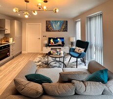 Una sala moderna con un sofá, sillones, una mesa de centro y un televisor.