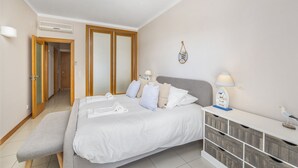 A bedroom with a bed, bedside tables, a bench, and a wardrobe.