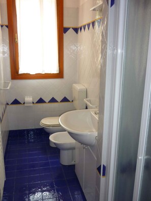 Un baño con dos inodoros, un lavabo y una ventana.