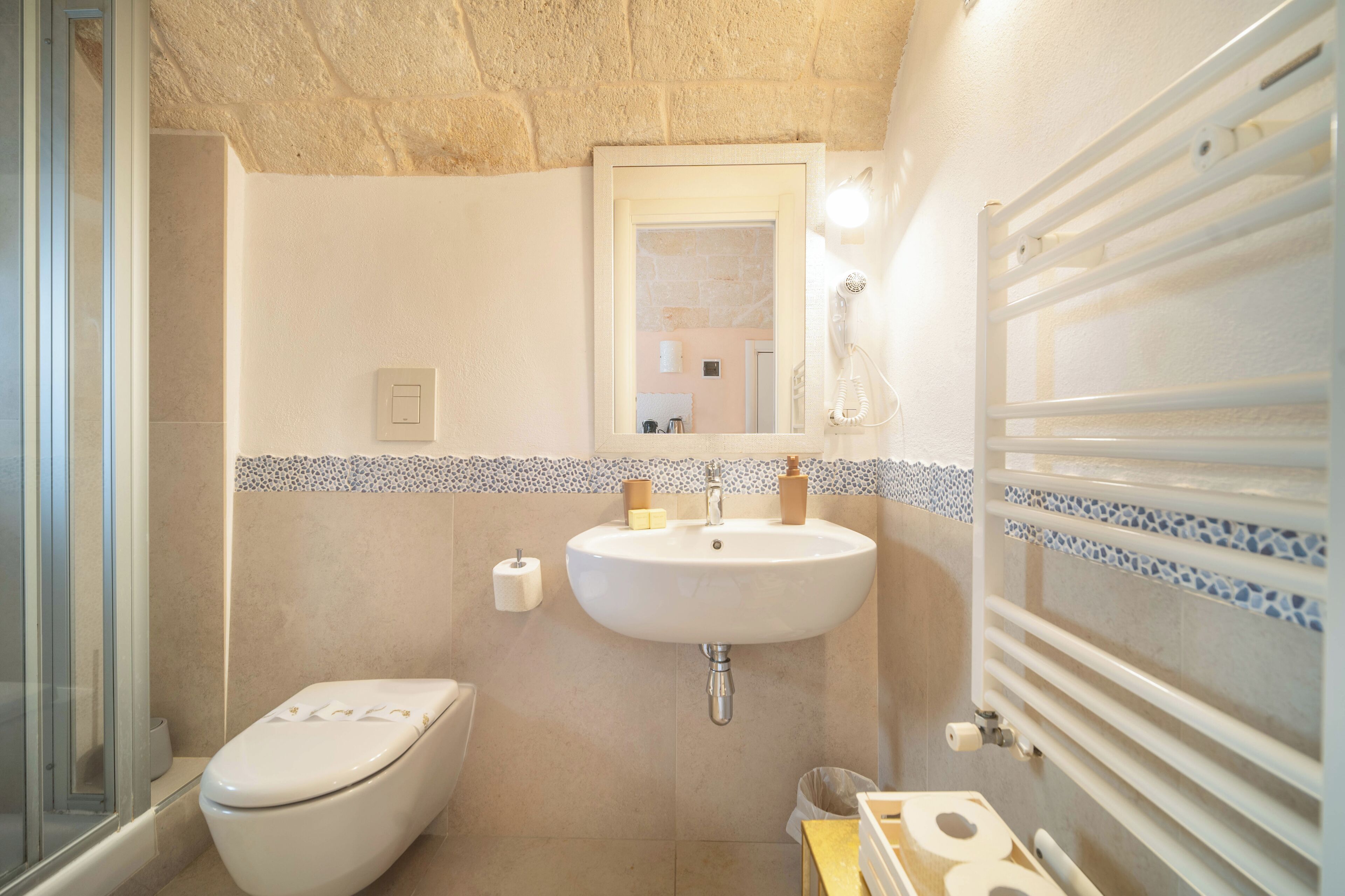 Un bagno con WC, lavandino, specchio e doccia.