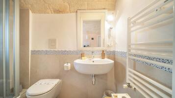 Un bagno con WC, lavandino, specchio e doccia.