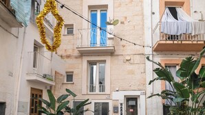 A courtyard with potted plants, a bicycle, and a building with balconies. - Le Contrade Chiasso Cafaro (Monopoli)