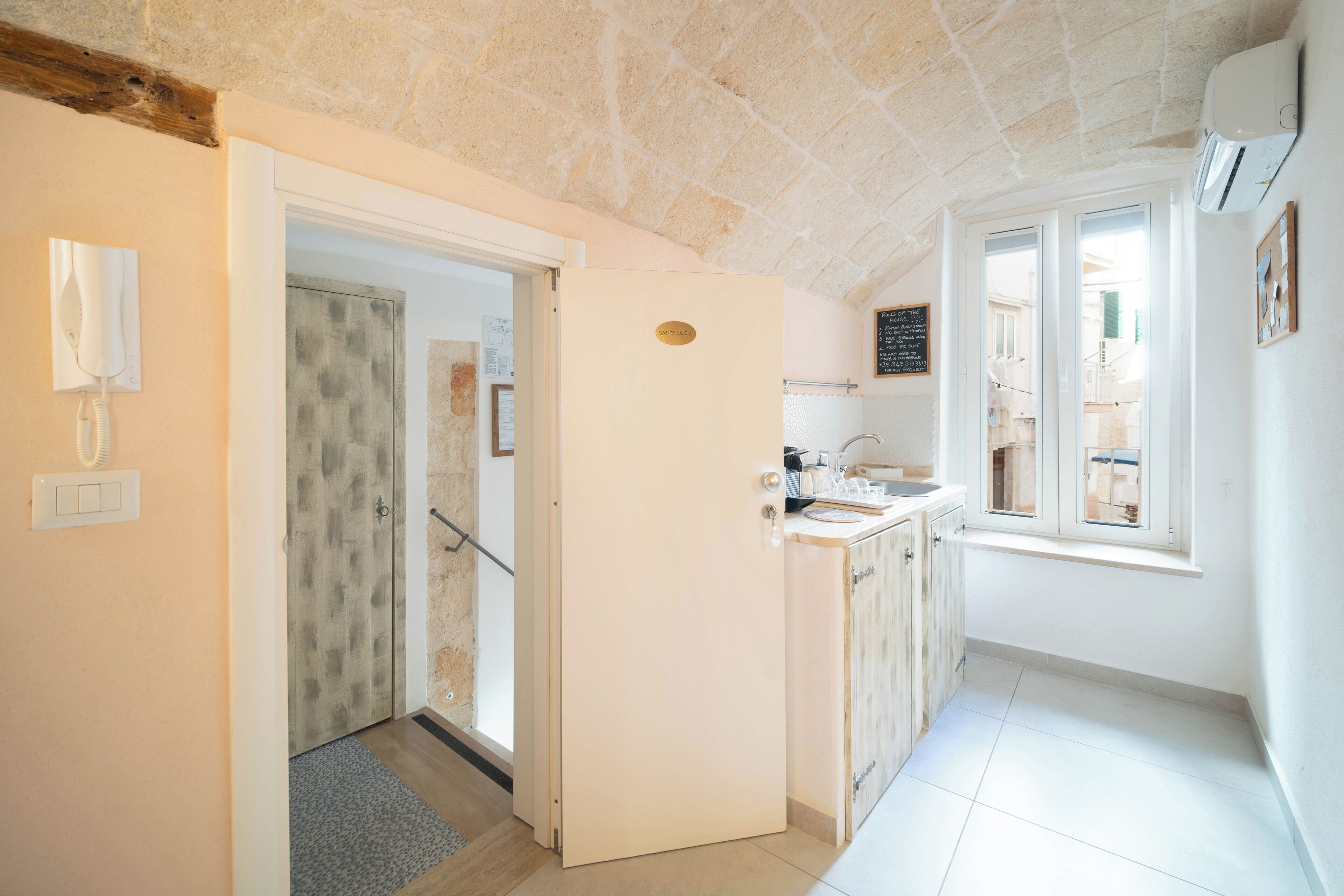 A kitchen with a window, a door, and a light switch on the wall.