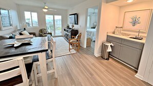 A spacious living area with a dining table, chairs, a sofa, and a view of the outdoors. - Gulf Shores Plantation IV (Gulf Shores)