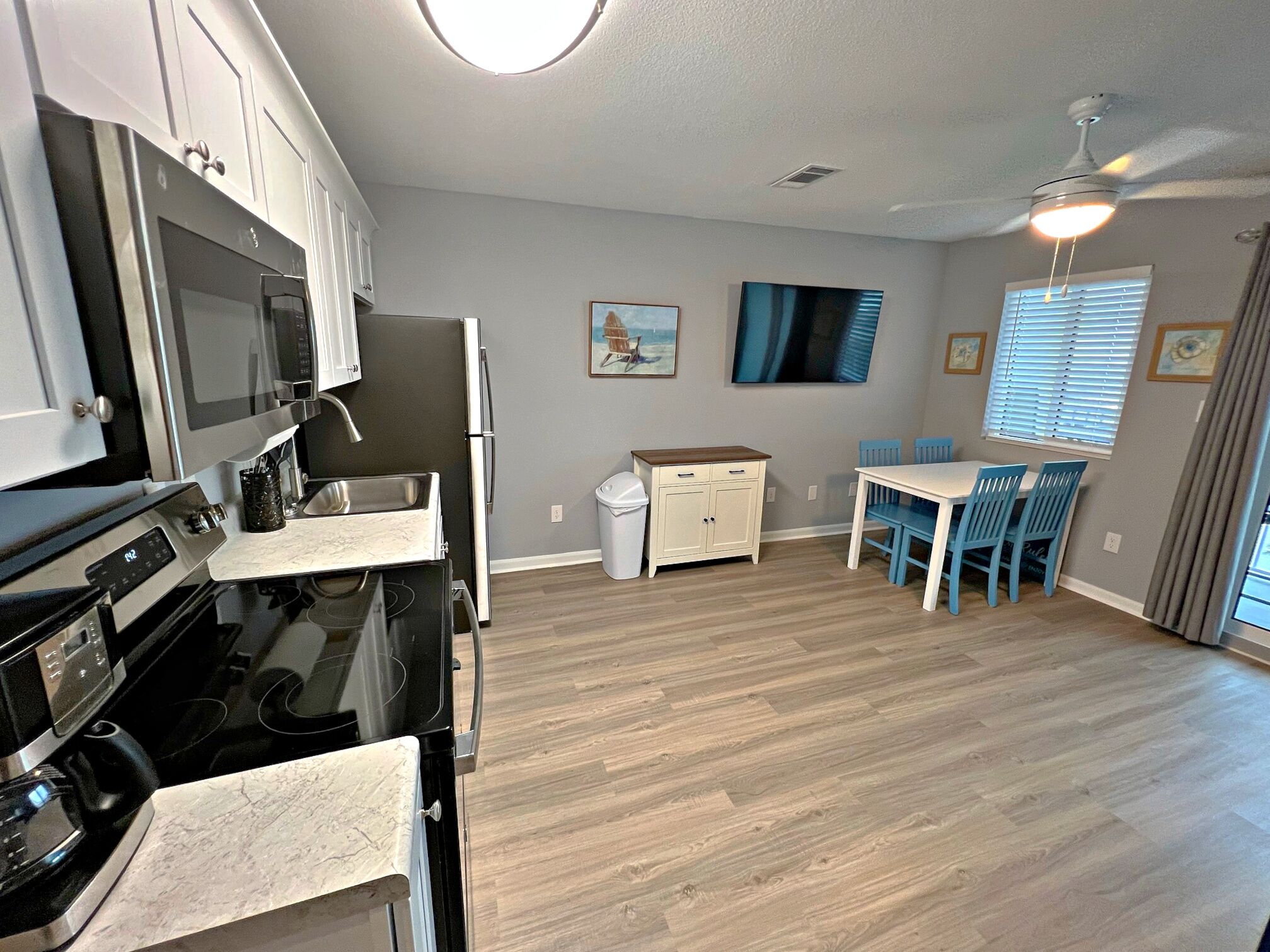 A modern kitchen with a stove, microwave, and refrigerator. There is a dining area with a table and chairs.