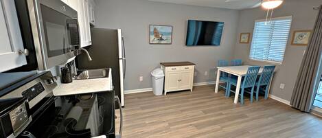 A modern kitchen with a stove, microwave, and refrigerator. There is a dining area with a table and chairs.