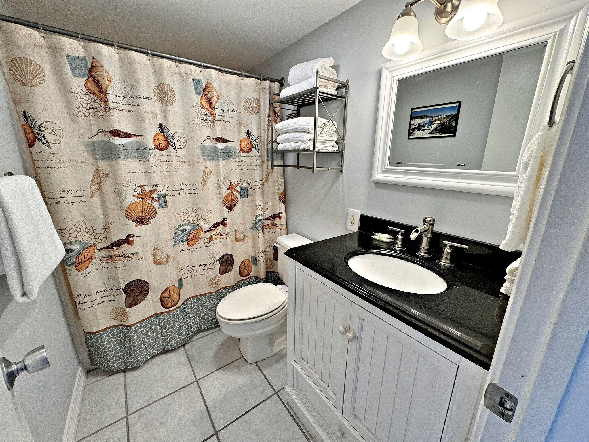 A bathroom with a toilet, sink, and shower curtain with sea creature designs.