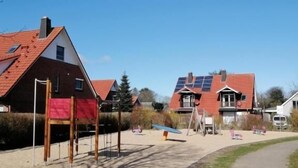 Een woonwijk met huizen, een speeltuin en een onverhard pad.