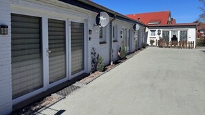 Een rij gelijkvloerse gebouwen met gesloten garage deuren, een heldere lucht, en een gebouw met een rood dak in de achtergrond.