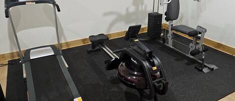 A gym with a treadmill, weight bench, and various exercise machines.