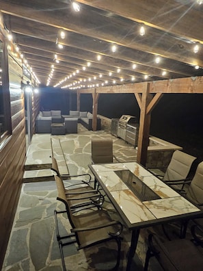 An outdoor patio with stone flooring, a long dining table, and multiple seating arrangements.