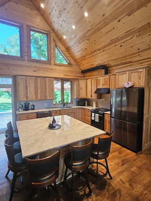 Una cocina amplia con armarios de madera, una isla grande y un refrigerador de acero inoxidable.