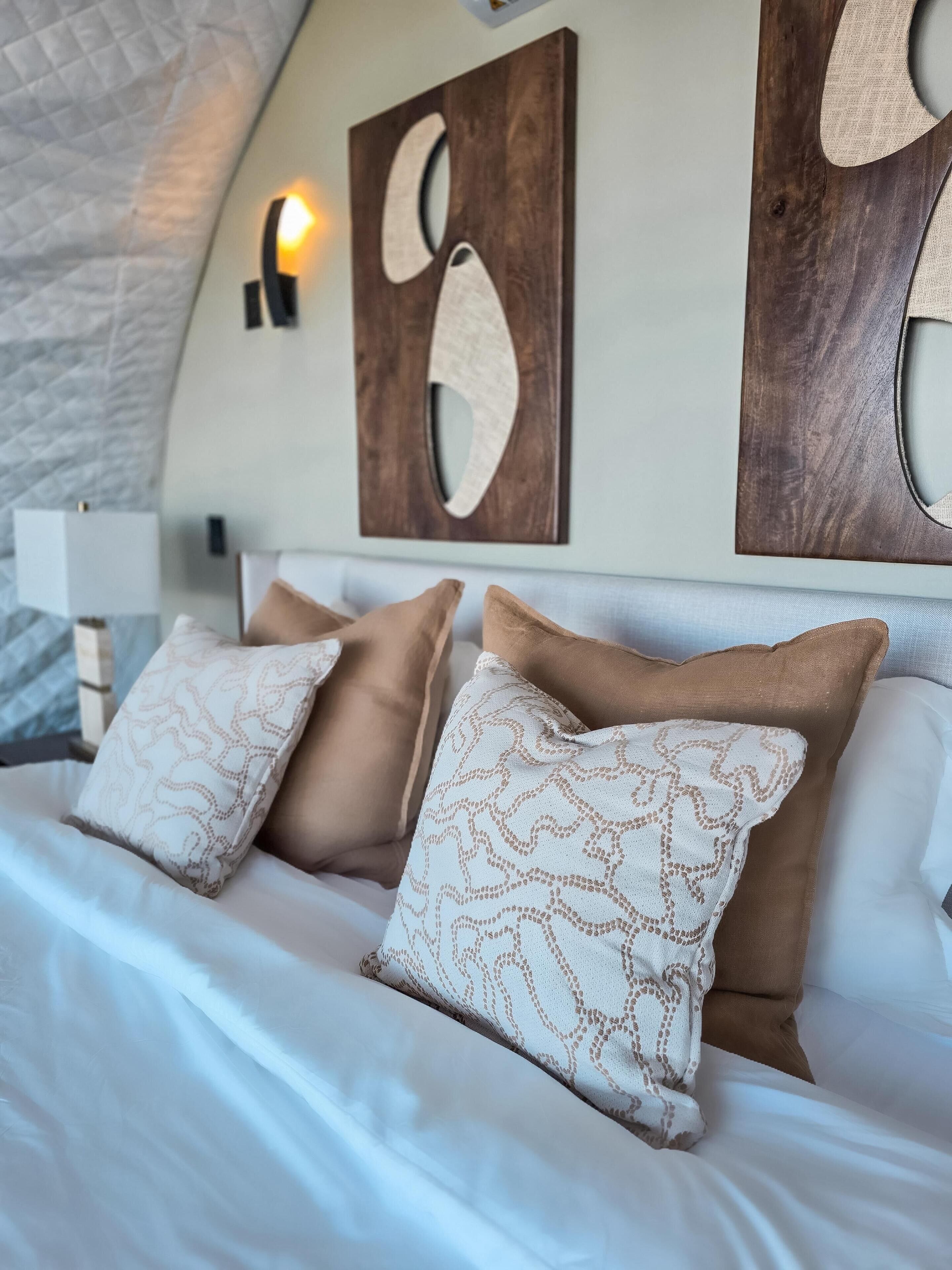 Un dormitorio con cama, almohadas y decoración en la pared.
