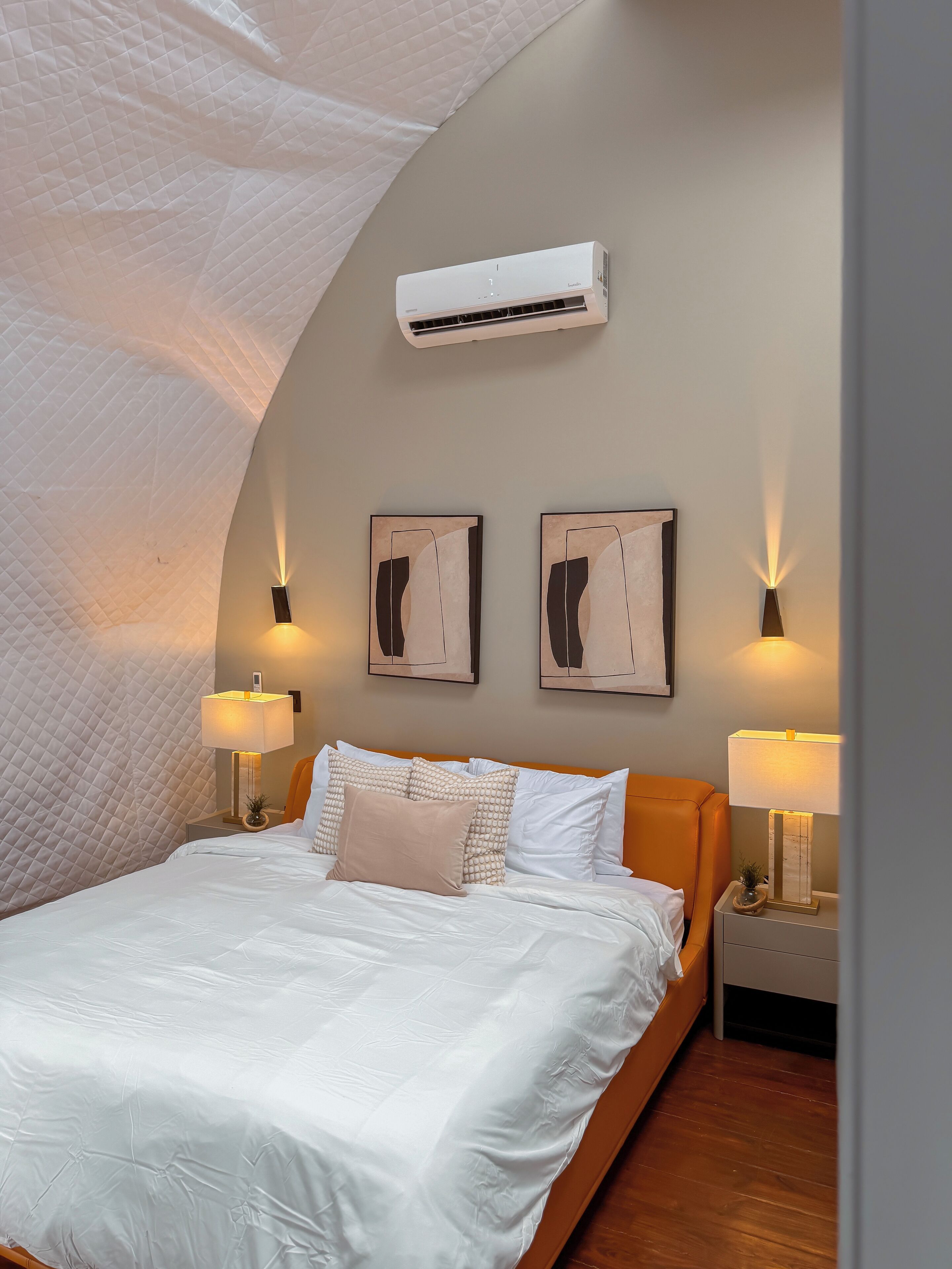 A neatly made bed with white linens, two wall-mounted lamps, and a ceiling fan.